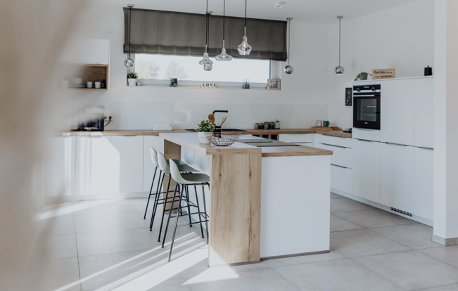 Helle Designküche mit großer Kochinsel, Holzdetails und Hängelampen in modernem, offenem Raumkonzept.